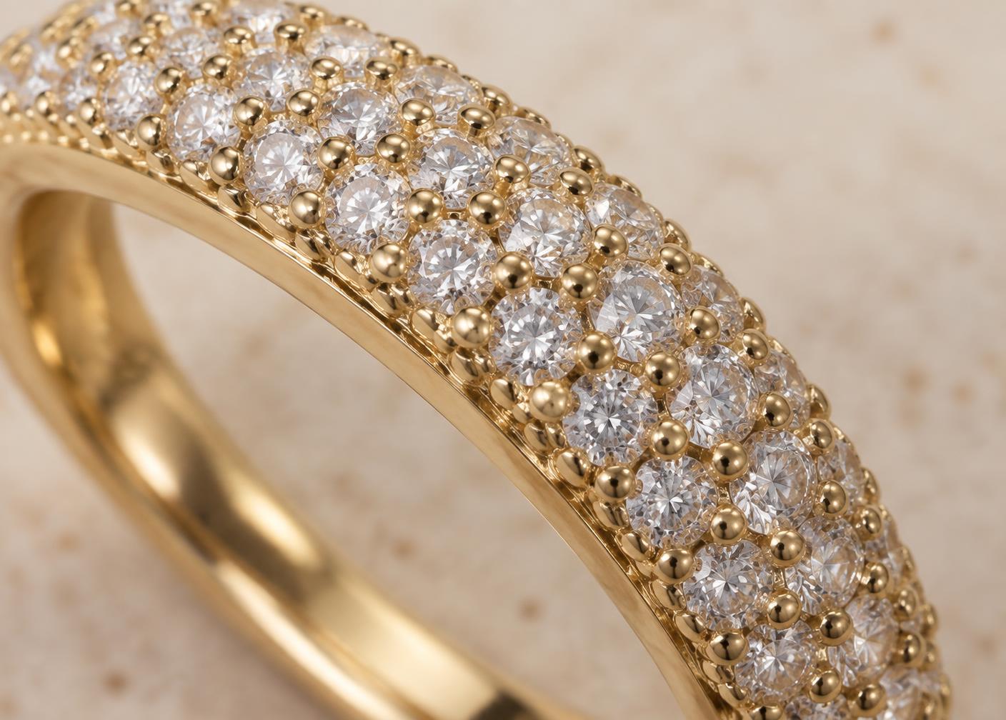 Tiny beads of metal securing closely set diamonds along a gold band